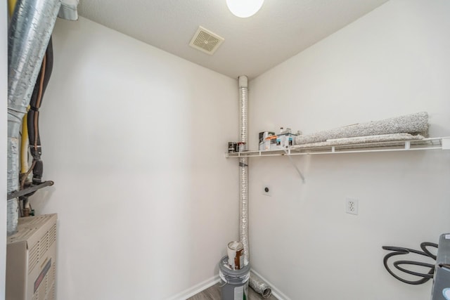 laundry area with laundry area, baseboards, visible vents, wood finished floors, and electric dryer hookup