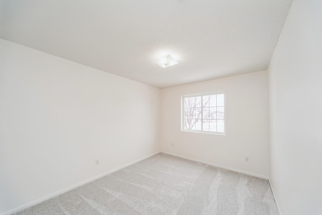 empty room featuring baseboards and light colored carpet