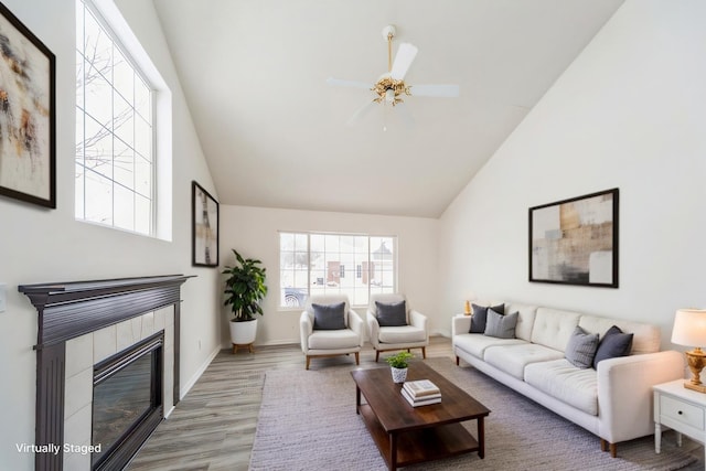 living room with a fireplace, ceiling fan, wood finished floors, high vaulted ceiling, and baseboards