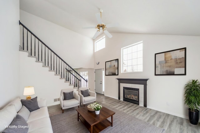 living room featuring a tile fireplace, wood finished floors, visible vents, and stairs