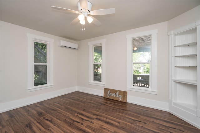 spare room with built in features, an AC wall unit, dark wood finished floors, and baseboards