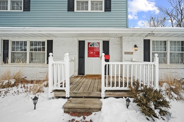 snow covered property entrance featuring a porch