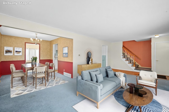 living room with a wainscoted wall, visible vents, a notable chandelier, wallpapered walls, and stairs