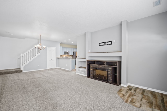 living room with baseboards, visible vents, a tiled fireplace, stairway, and an inviting chandelier