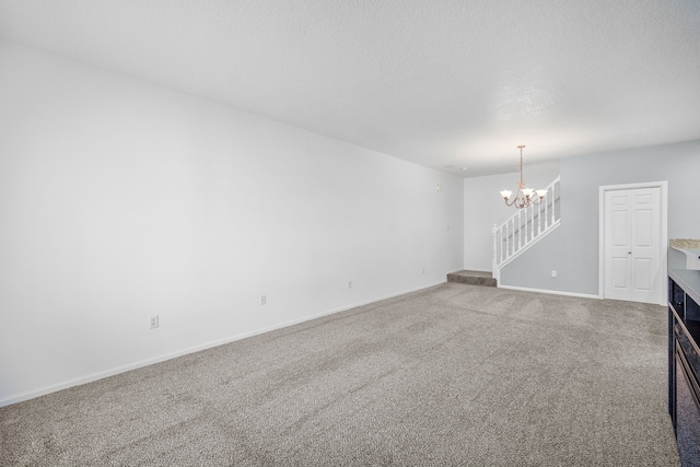 unfurnished living room featuring stairs, carpet floors, a textured ceiling, and a chandelier