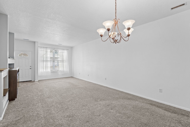 interior space with visible vents, an inviting chandelier, carpet flooring, a textured ceiling, and baseboards