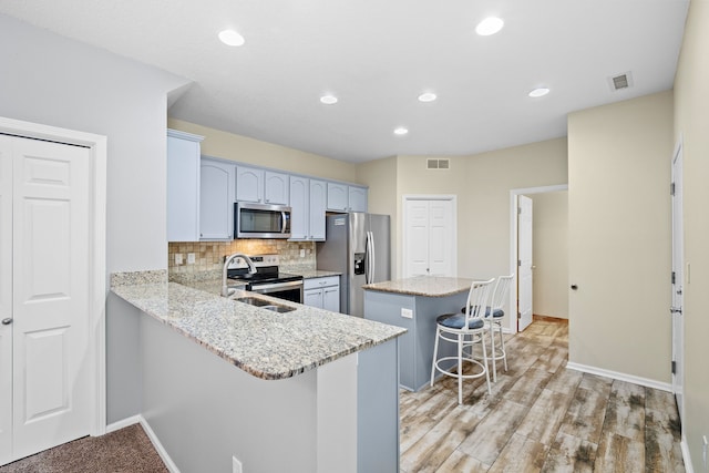 kitchen with a peninsula, visible vents, appliances with stainless steel finishes, and a kitchen breakfast bar