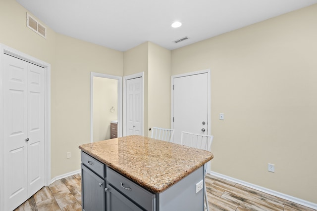 kitchen featuring baseboards, a kitchen island, visible vents, and gray cabinetry