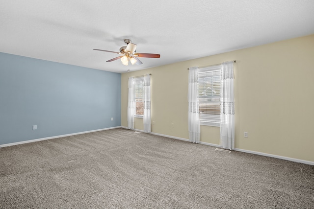 spare room with carpet floors, a textured ceiling, baseboards, and a ceiling fan