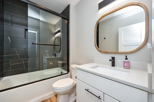 bathroom with enclosed tub / shower combo, vanity, and toilet