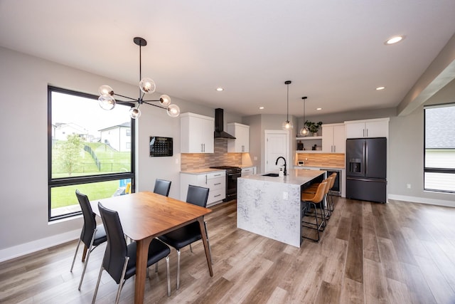 dining space featuring beverage cooler, a healthy amount of sunlight, baseboards, and light wood finished floors