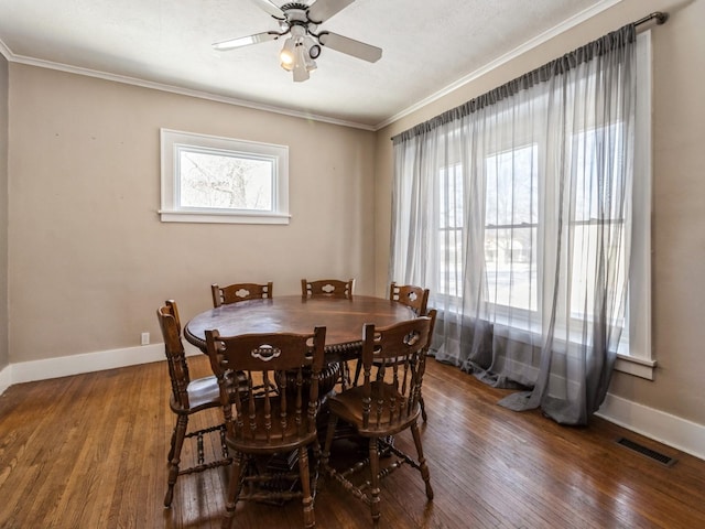 dining room with baseboards, visible vents, dark wood finished floors, and crown molding