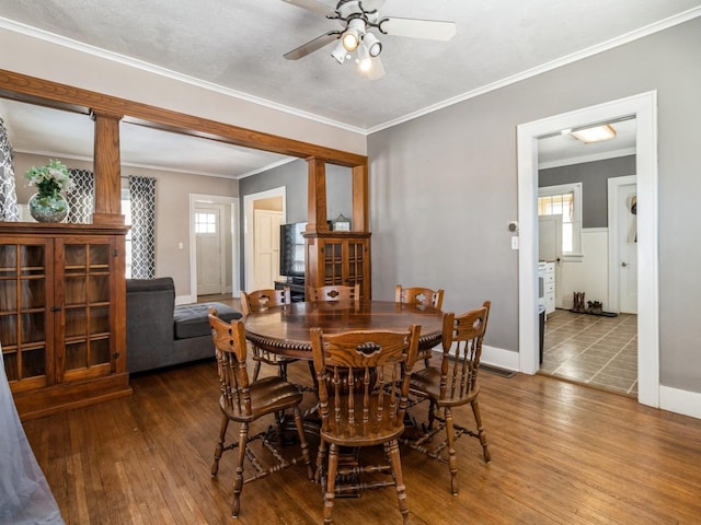 dining space with decorative columns, baseboards, ceiling fan, ornamental molding, and wood finished floors