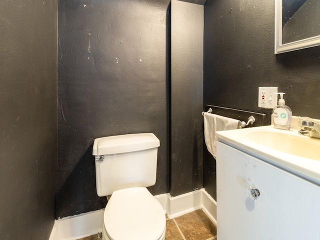 bathroom featuring toilet, a textured wall, tile patterned floors, and vanity