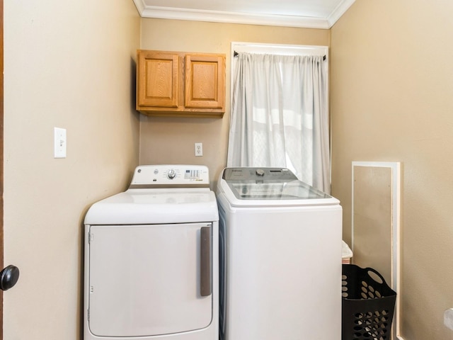 washroom with ornamental molding, cabinet space, and washing machine and clothes dryer