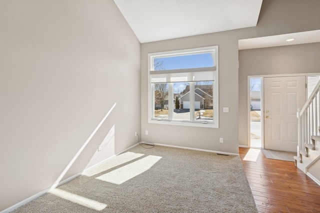 interior space featuring visible vents, baseboards, lofted ceiling, wood finished floors, and stairs