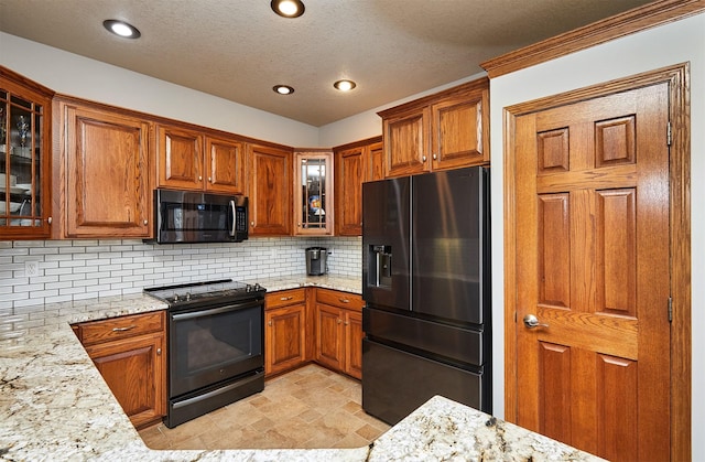 kitchen with brown cabinetry, black electric range, stainless steel microwave, and fridge with ice dispenser