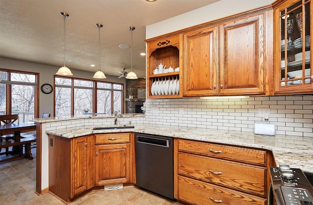 kitchen featuring dishwasher, stone finish floor, brown cabinets, a peninsula, and a sink