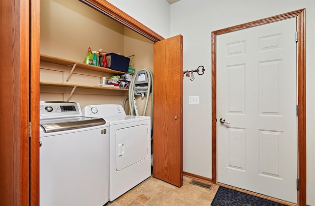 clothes washing area with laundry area, washing machine and clothes dryer, visible vents, and baseboards