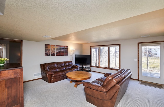 living area with light carpet, a textured ceiling, visible vents, and baseboards