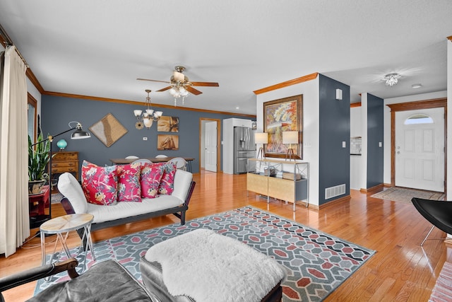 living area featuring ornamental molding, wood finished floors, visible vents, and baseboards