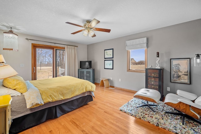 bedroom with access to exterior, ceiling fan, a textured ceiling, wood finished floors, and baseboards