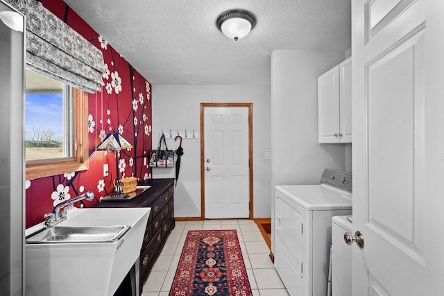 washroom with cabinet space, light tile patterned floors, a textured ceiling, separate washer and dryer, and a sink