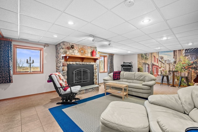 living room featuring a fireplace, baseboards, a drop ceiling, and recessed lighting