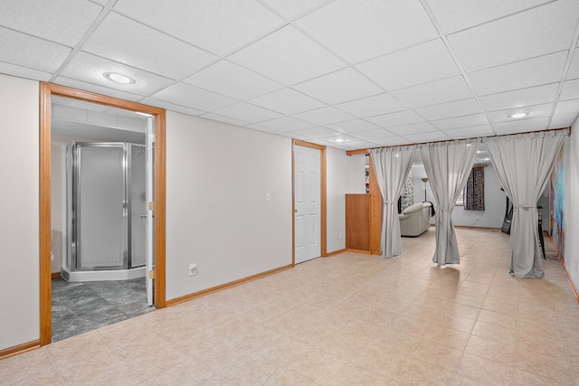 finished below grade area with a paneled ceiling, recessed lighting, baseboards, and tile patterned floors