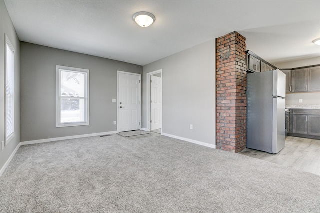 unfurnished room with visible vents, baseboards, and light colored carpet