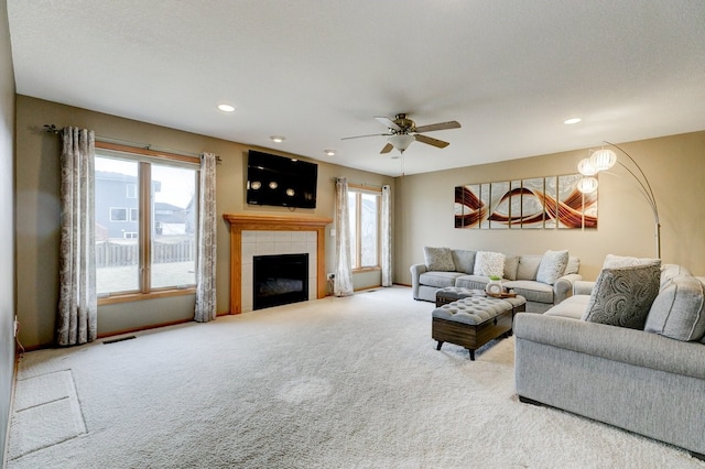 living room featuring light carpet, a wealth of natural light, a tiled fireplace, and visible vents