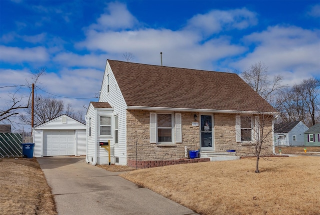 view of front of home with concrete driveway, stone siding, a detached garage, roof with shingles, and an outbuilding