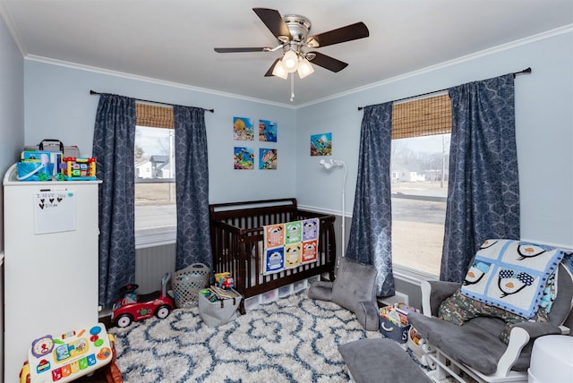 bedroom featuring ornamental molding, a crib, and a ceiling fan