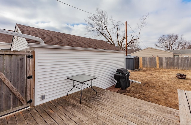 wooden deck with a shed, fence, and an outbuilding