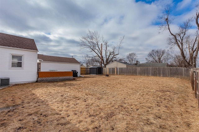 view of yard with a shed, an outbuilding, cooling unit, and a fenced backyard