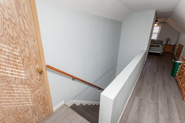 staircase with vaulted ceiling, wood finished floors, and baseboards