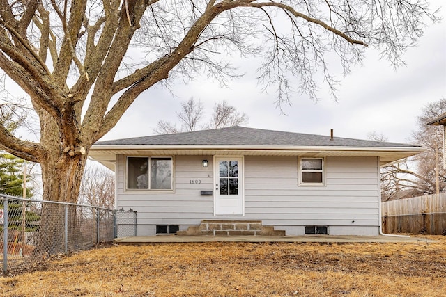 view of front of house with entry steps, roof with shingles, and fence