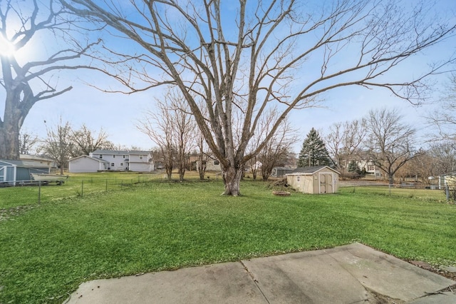 view of yard with a residential view, fence, a storage unit, and an outbuilding