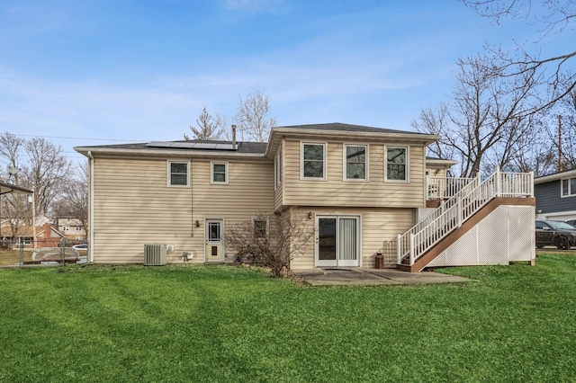 back of property featuring a yard, stairway, a wooden deck, and solar panels