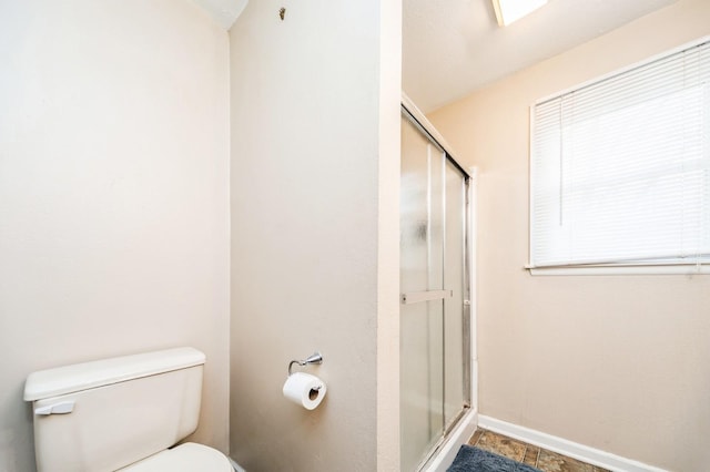 full bath with toilet, a stall shower, and baseboards