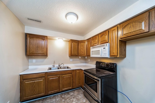 kitchen with light countertops, visible vents, white microwave, stainless steel range with electric cooktop, and a sink