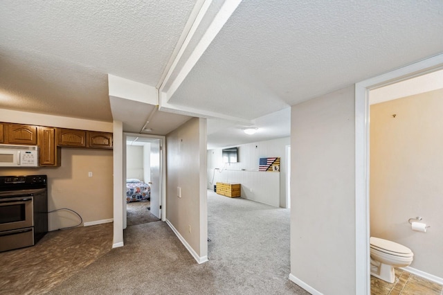 hallway featuring light carpet, baseboards, and a textured ceiling