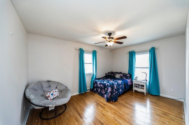 bedroom featuring a ceiling fan, baseboards, and wood finished floors