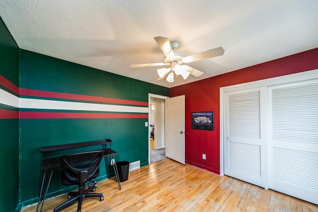 office area with light wood finished floors, visible vents, baseboards, a ceiling fan, and a textured ceiling