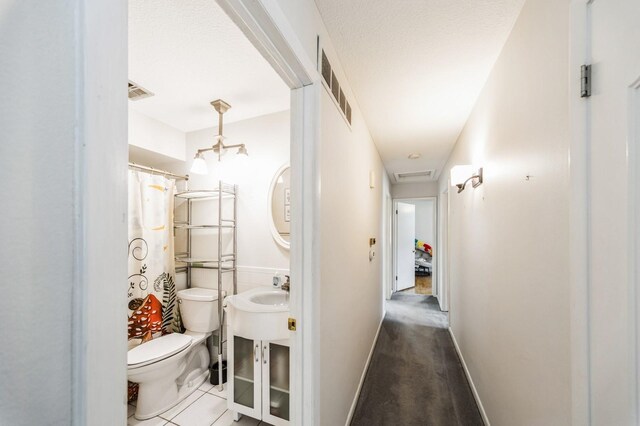 hall with baseboards, visible vents, a sink, and tile patterned floors