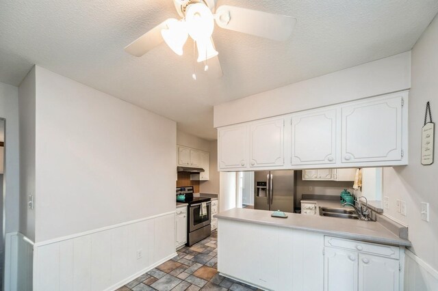 kitchen with stainless steel appliances, a peninsula, a sink, white cabinetry, and light countertops