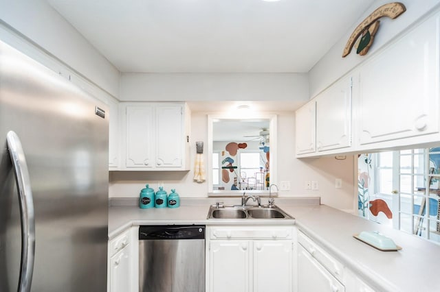 kitchen featuring appliances with stainless steel finishes, light countertops, white cabinetry, and a sink