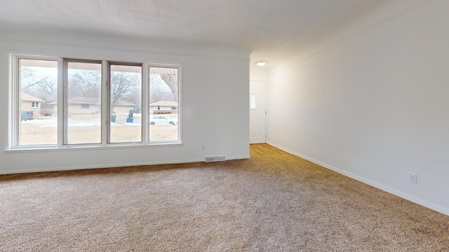 spare room with visible vents, baseboards, and light colored carpet