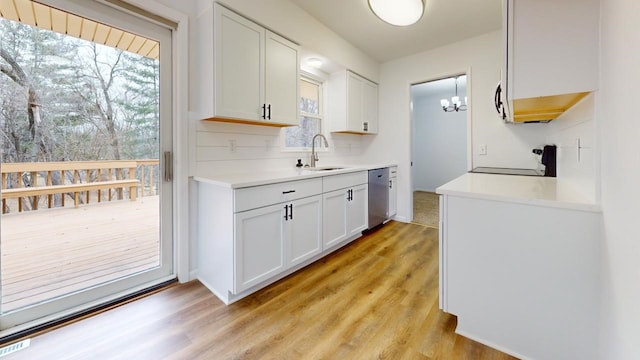 kitchen featuring dishwasher, light countertops, stove, white cabinets, and a sink