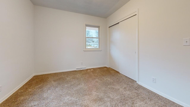 unfurnished bedroom with carpet, visible vents, a closet, and baseboards